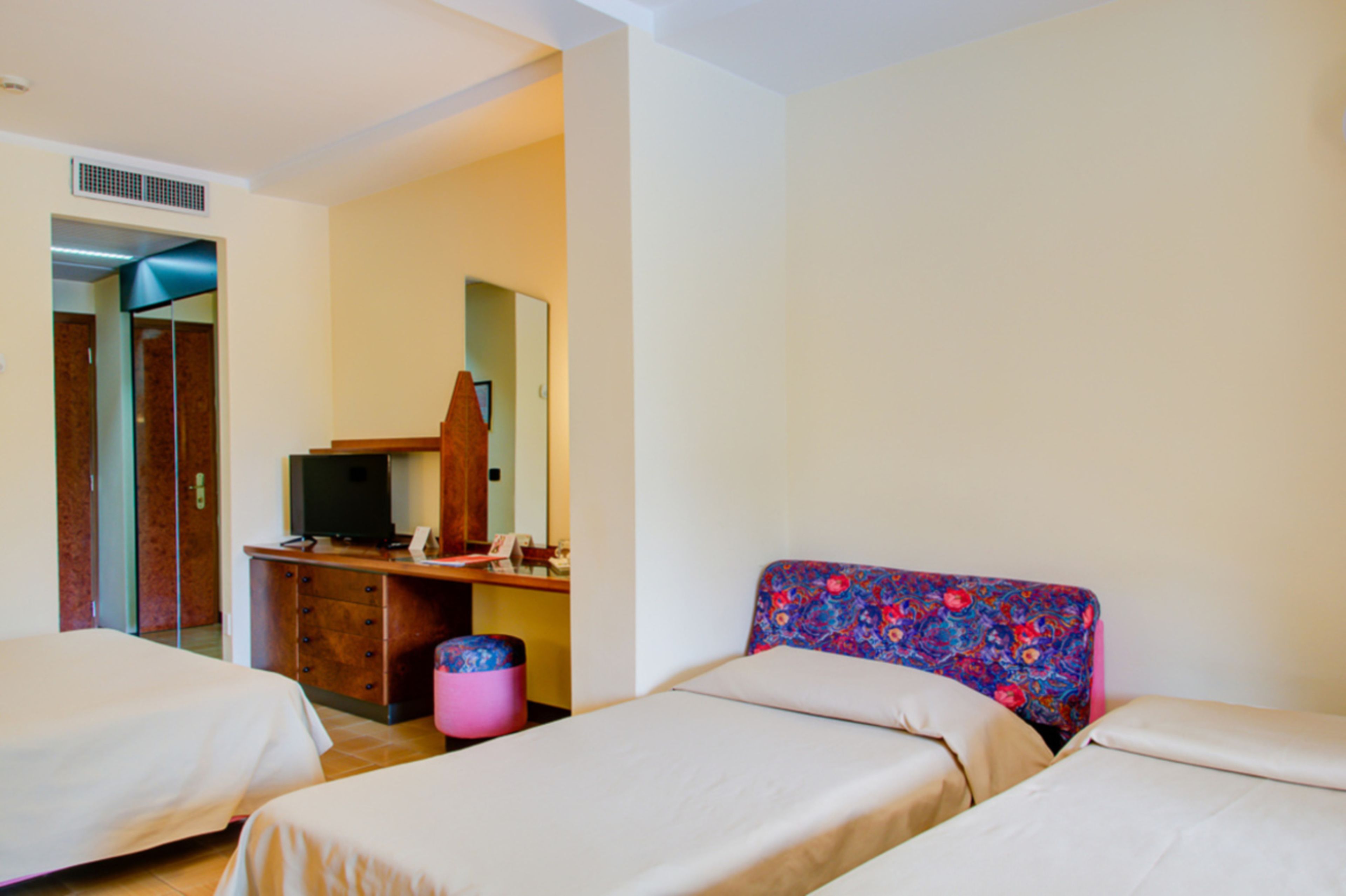 Une chambre d’hôtel avec deux lits, un bureau avec une télévision et un miroir.