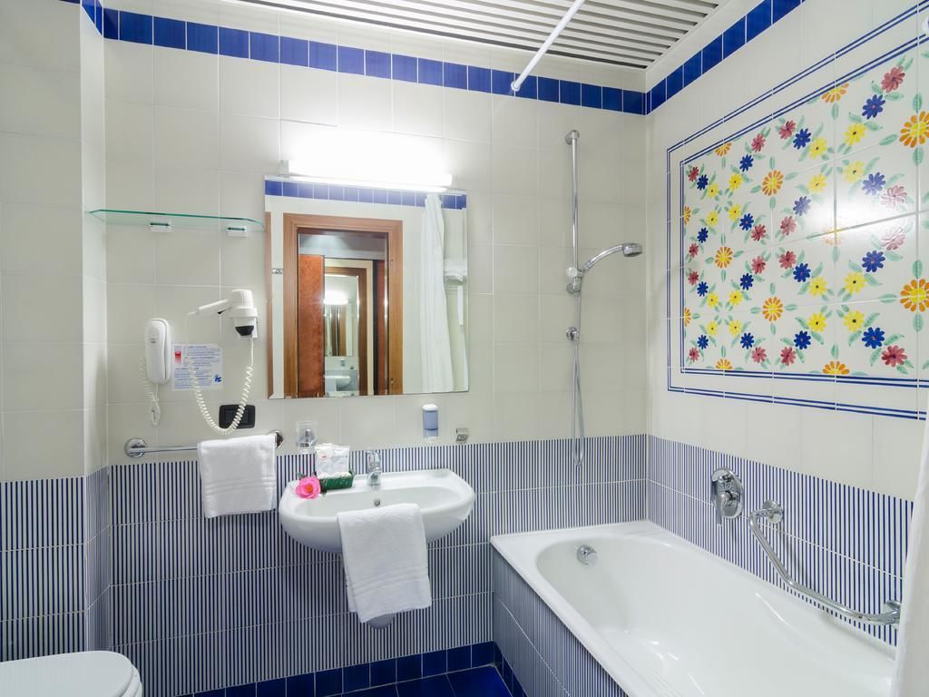 A bathroom with a sink, mirror, and bathtub.