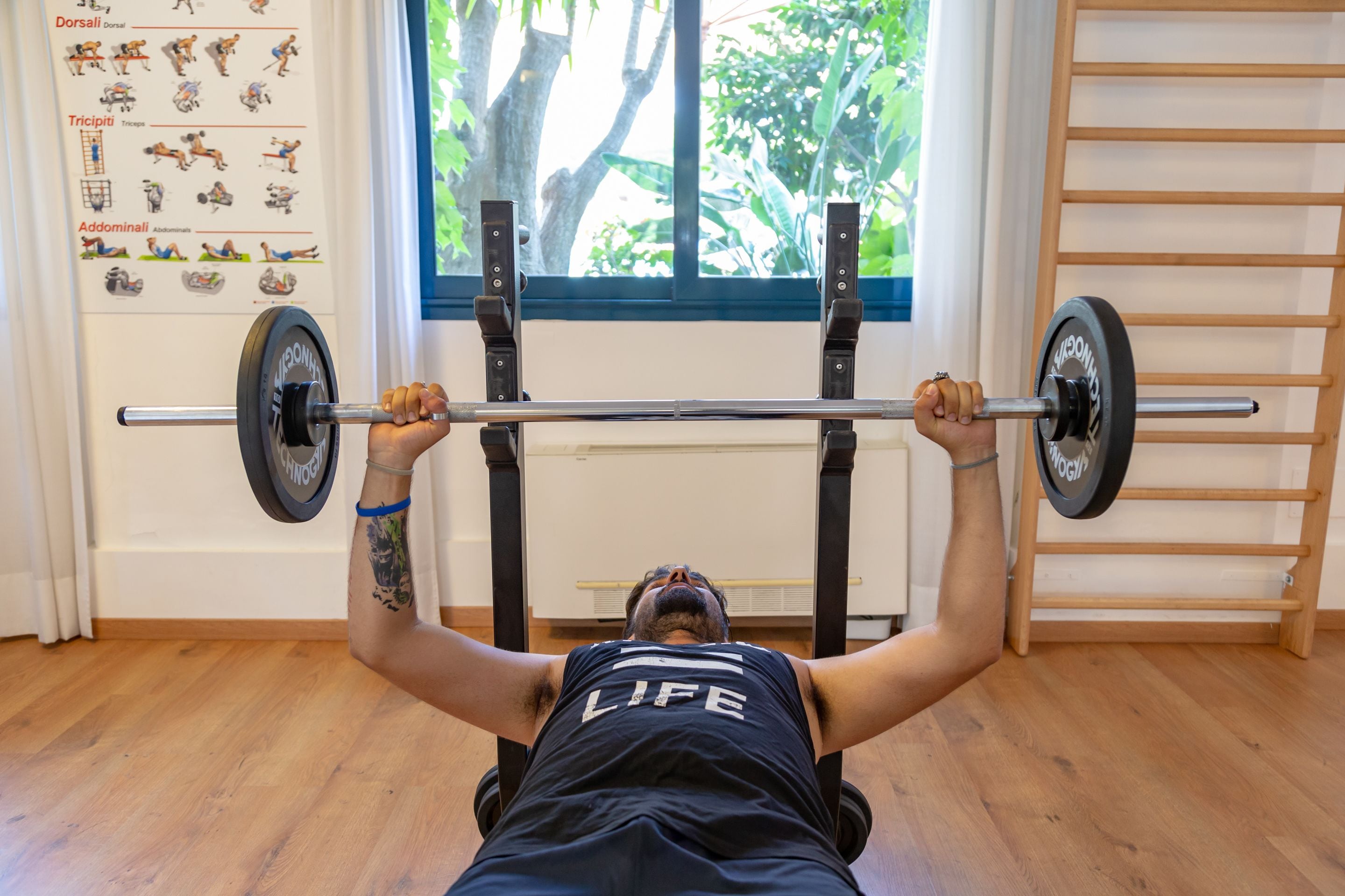 A person lying on a bench, performing a bench press exercise with a barbell.