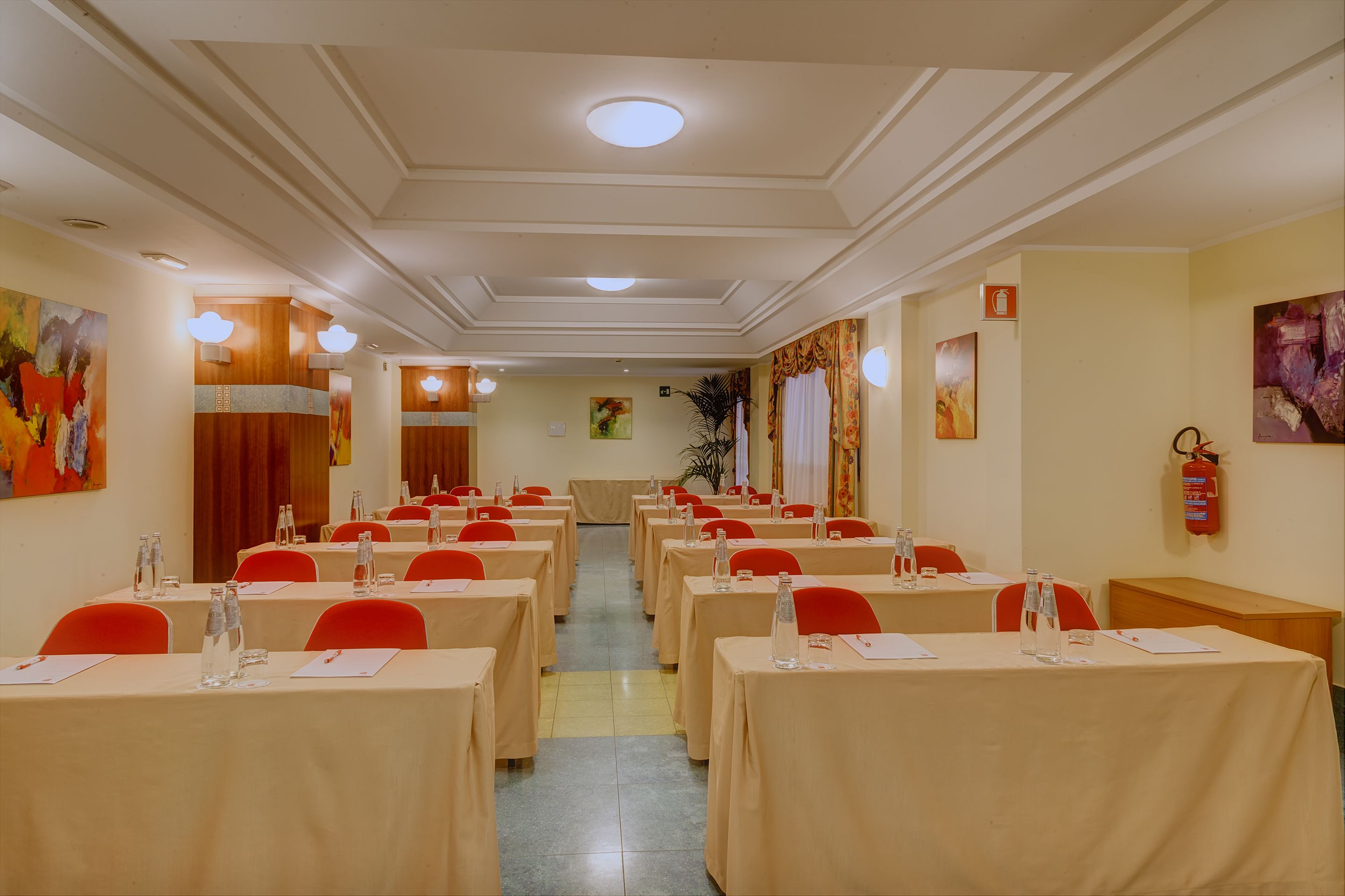 A conference room with rows of tables, chairs, and water bottles.