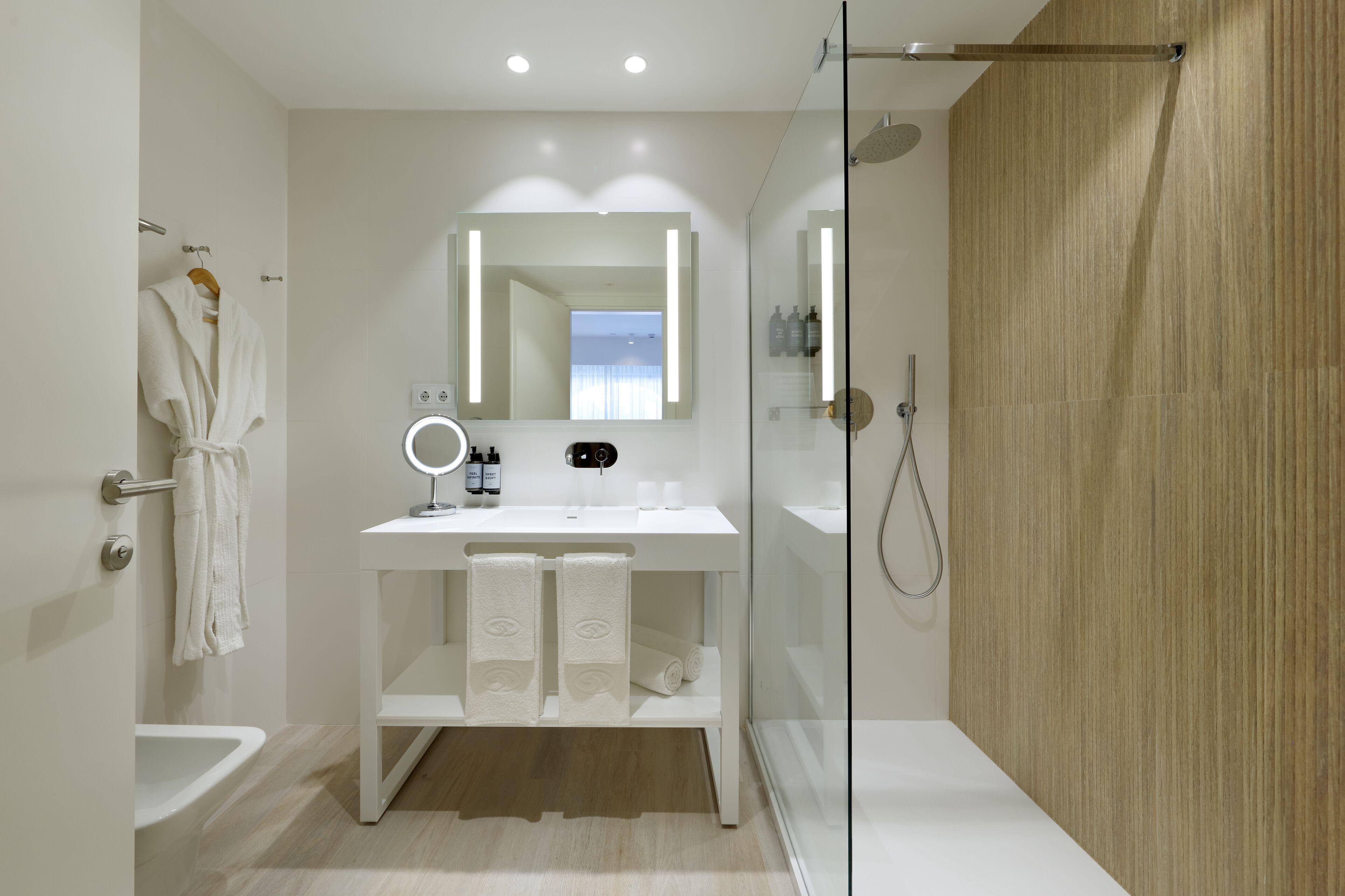 A modern bathroom with a glass shower enclosure, a white vanity with a mirror, and a towel rack.