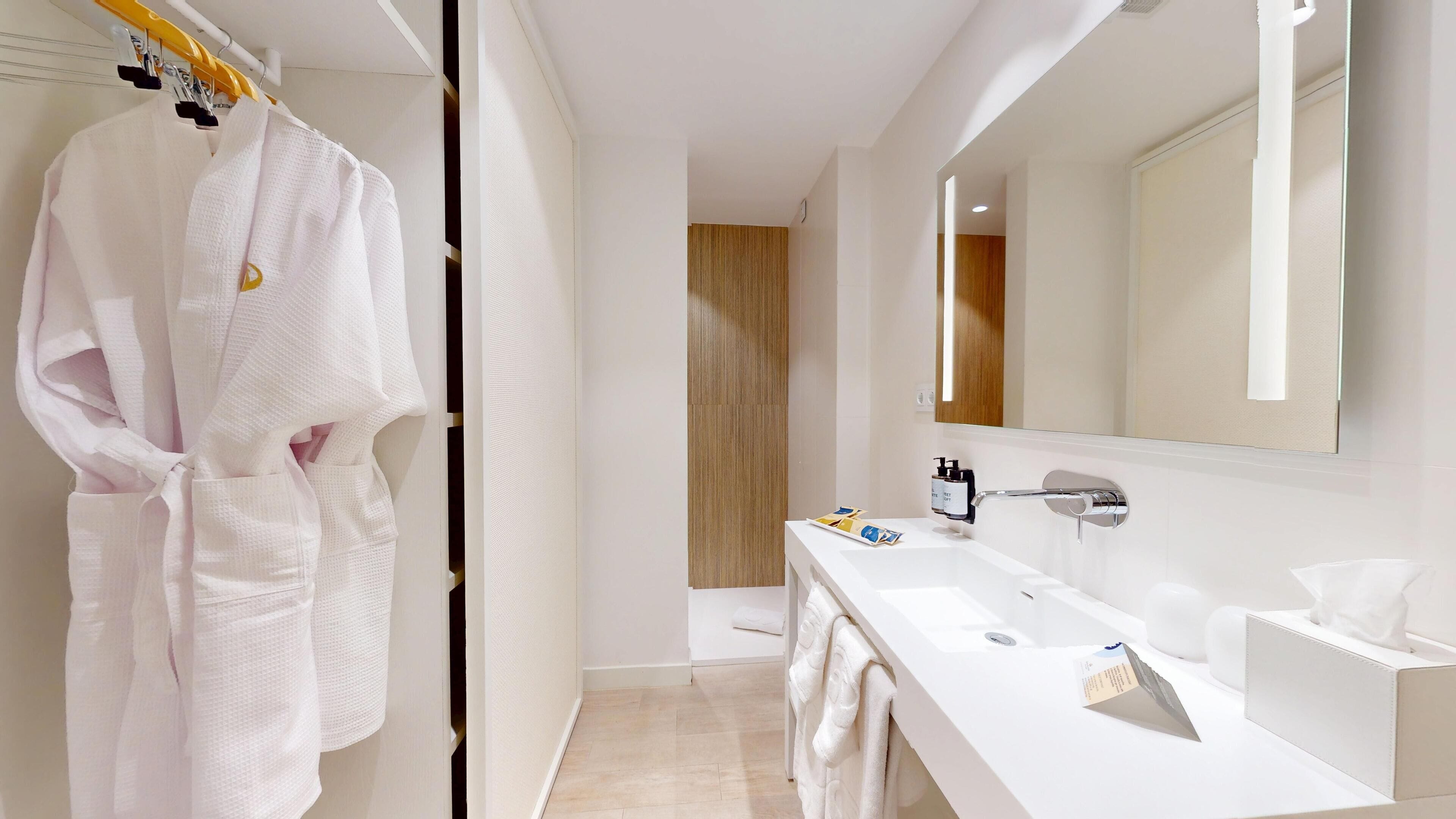 A modern bathroom with a white sink, mirror, and towel rack.