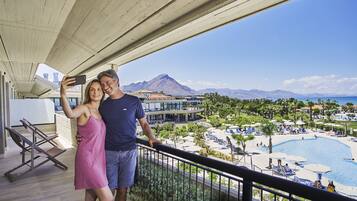 A balcony with a view of a resort pool and mountains.