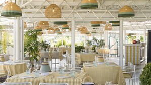 An outdoor restaurant with checkered tablecloths, wicker chairs, and hanging wicker lamps. - Grand Palladium Sicilia Resort & Spa  (Campofelice di Roccella)