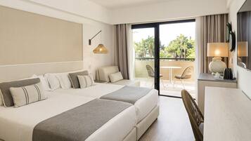 Ein Hotelzimmer mit einem großen Bett, einem Schreibtisch und einem Balkon mit Blick auf Grünflächen.