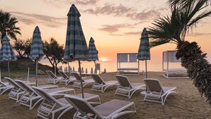 A beach with lounge chairs and striped umbrellas. - Grand Palladium Sicilia Resort & Spa  (Campofelice di Roccella)