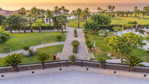 A landscaped garden with a pathway leading to a view of the sea, surrounded by palm trees and greenery. - Grand Palladium Sicilia Resort & Spa  (Campofelice di Roccella)