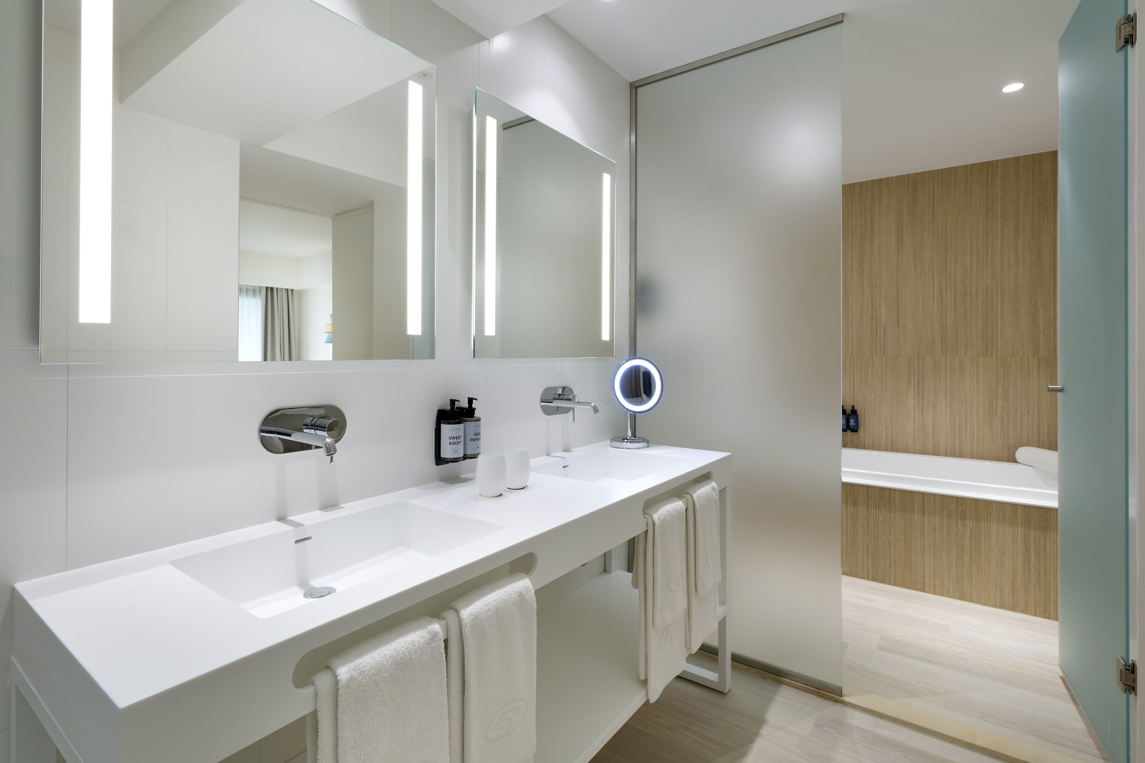 Un baño moderno con tocador blanco, un espejo grande y una pared de paneles de madera.