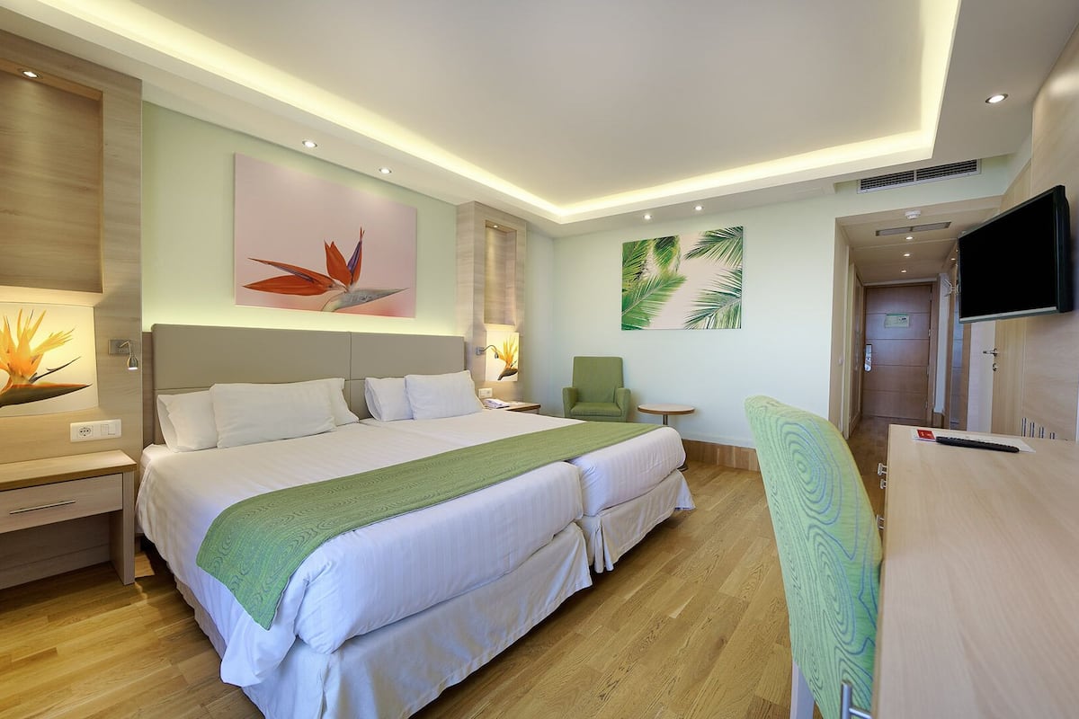 Une chambre d’hôtel avec un grand lit, un bureau, une chaise et un téléviseur.