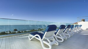 Terraza con tumbonas con vista a una playa y al océano.