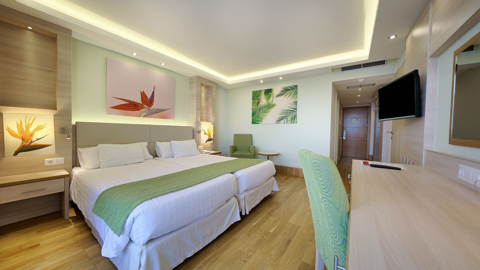 Une chambre d’hôtel avec un grand lit, un bureau, une chaise et un téléviseur.
