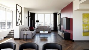 A modern living room with a sofa, coffee table, and chairs. There is a TV and artwork on the wall. - Four Points by Sheraton Levis Convention Centre (Levis)