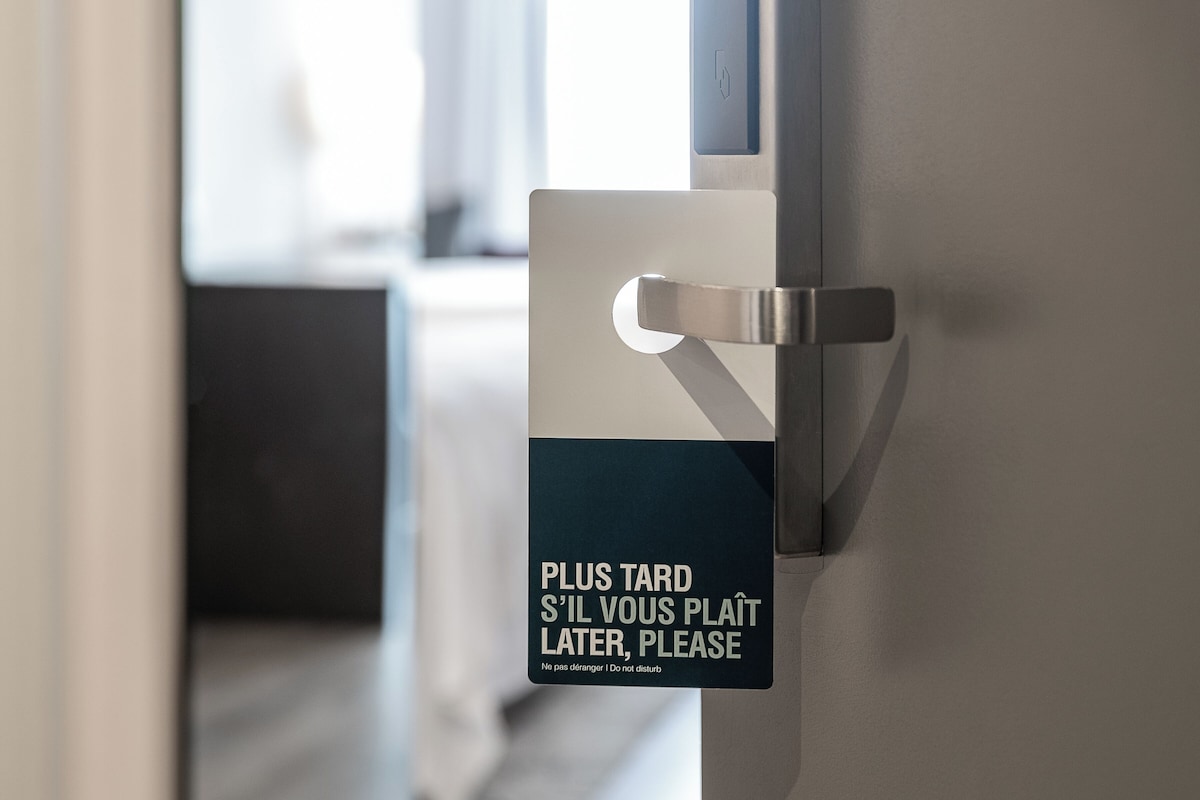 A door with a sign that reads "Plus tard s'il vous plaît later, please" in English and French.