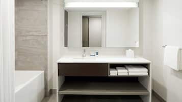 A modern bathroom with a bathtub, a sink with a mirror above it, and a towel rack on the wall.