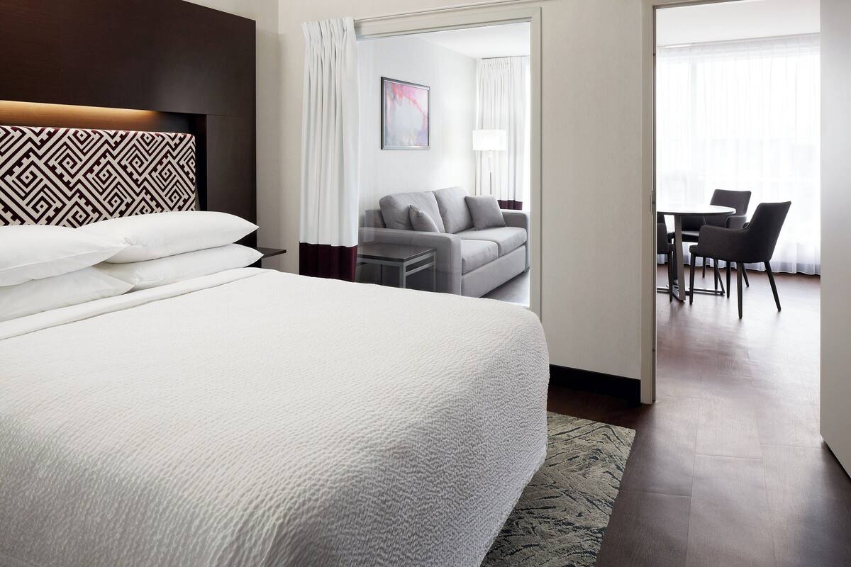 A hotel room with a large bed, a sofa, a desk, and chairs.