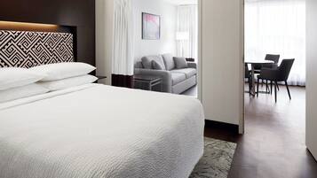 A hotel room with a large bed, a sofa, a desk, and chairs.