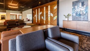 A modern conference room with a large table, several sofas, and a wooden partition with glass panels. - Four Points by Sheraton Levis Convention Centre (Levis)