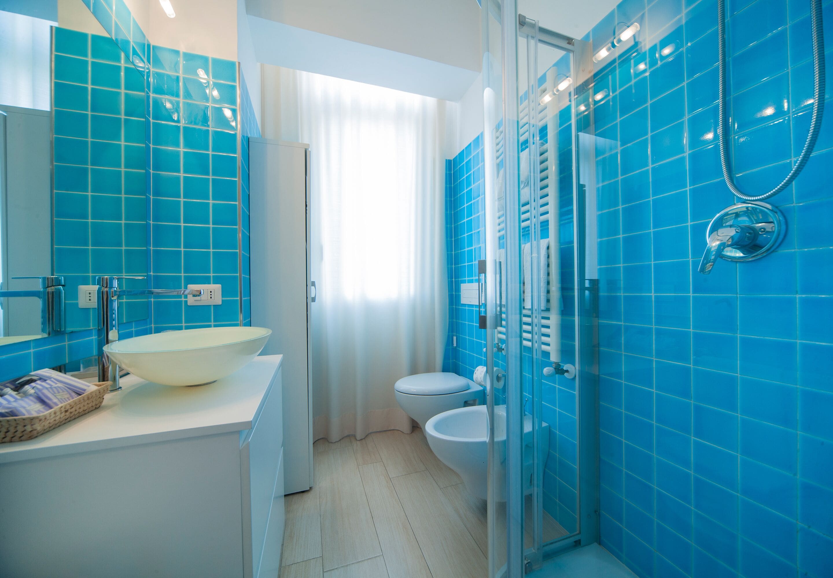 A modern bathroom with a large white sink, a toilet, and a glass-enclosed shower area.