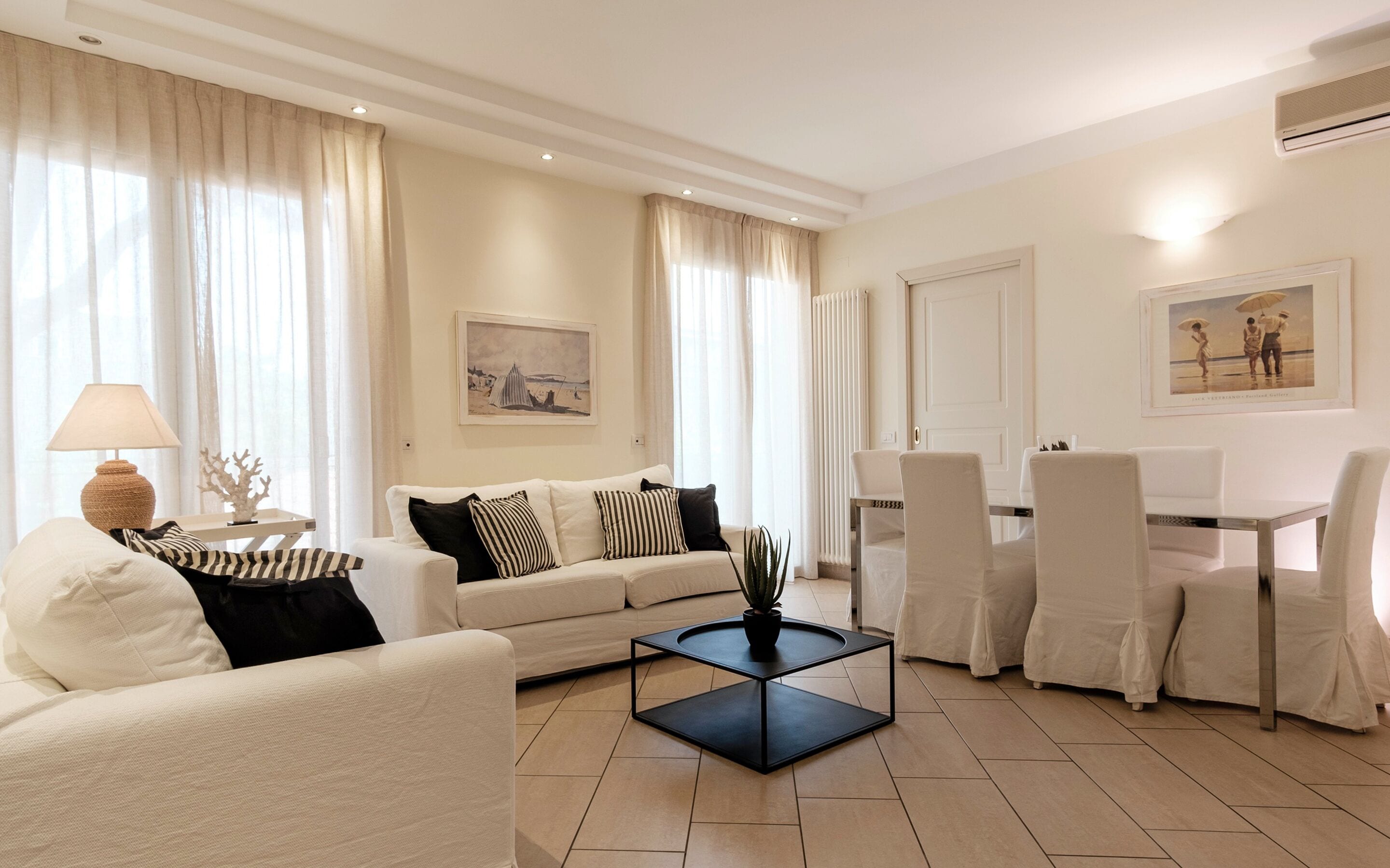 A modern living room with a sofa, a coffee table, and a dining area with chairs.