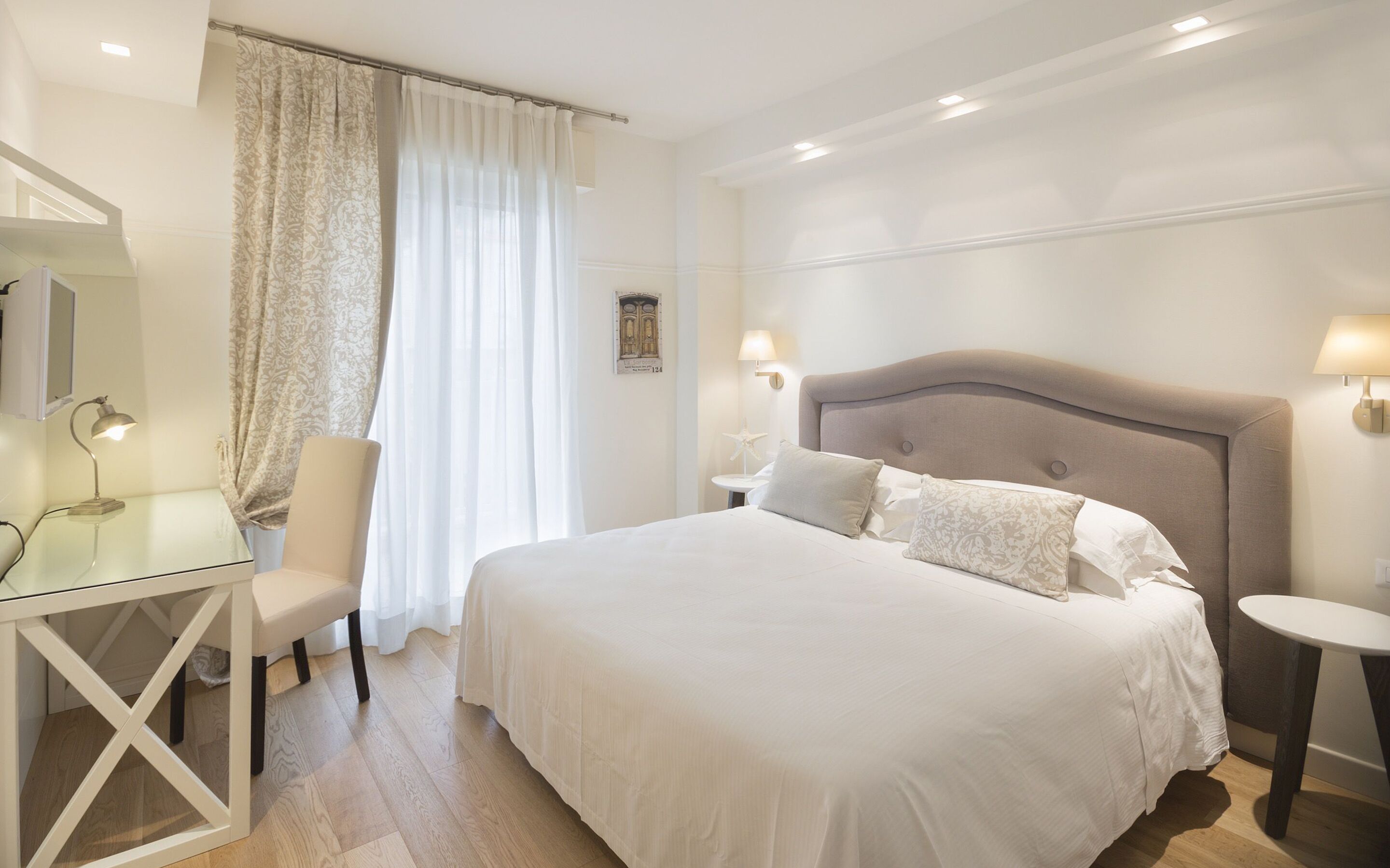 A bedroom with a large bed, bedside tables, a desk, and a chair.