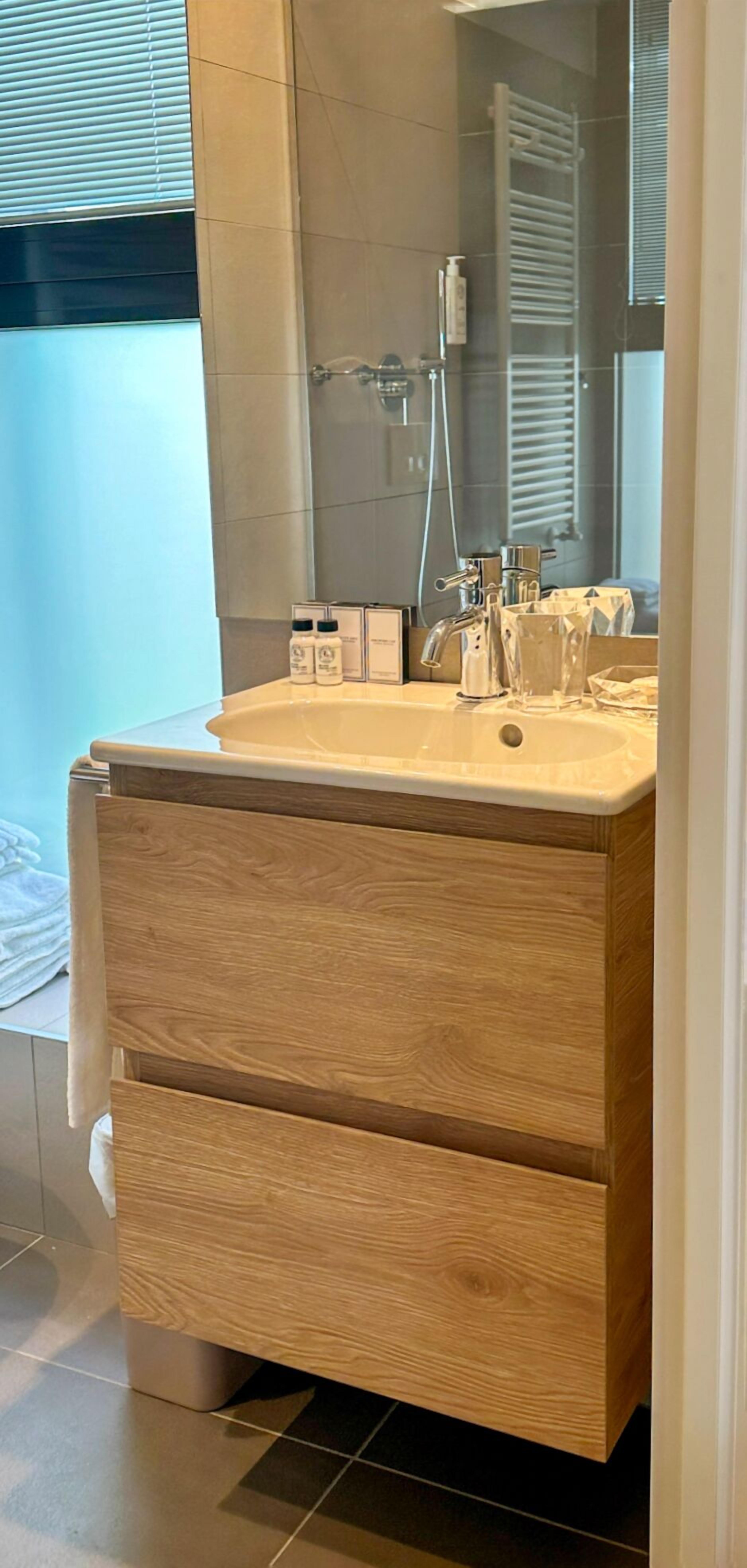 A bathroom with a wooden vanity, a sink, and a mirror.