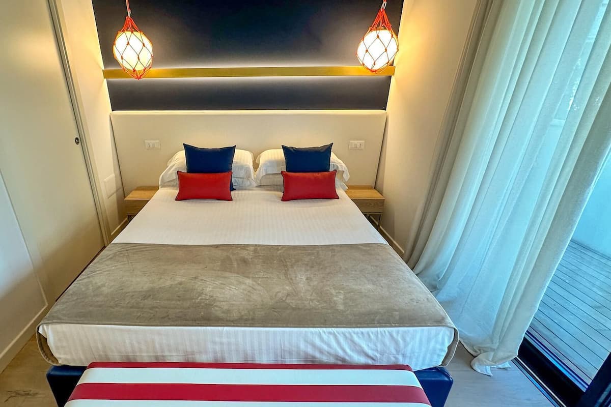 A hotel room with a large bed, two bedside tables, and a ceiling light fixture.