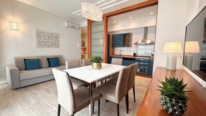 Una sala de estar moderna con comedor, cocina y un amplio ventanal.