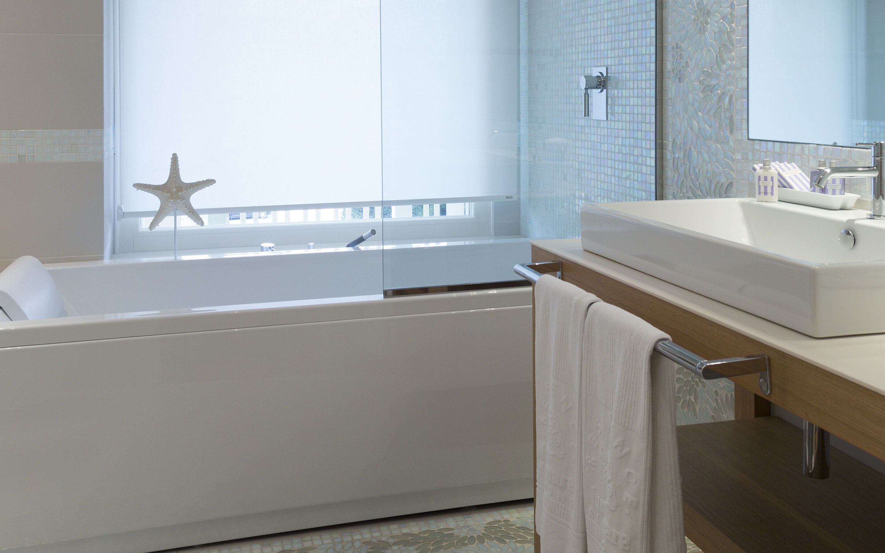 Un baño moderno con bañera, un espejo grande y una decoración con una estrella de mar.