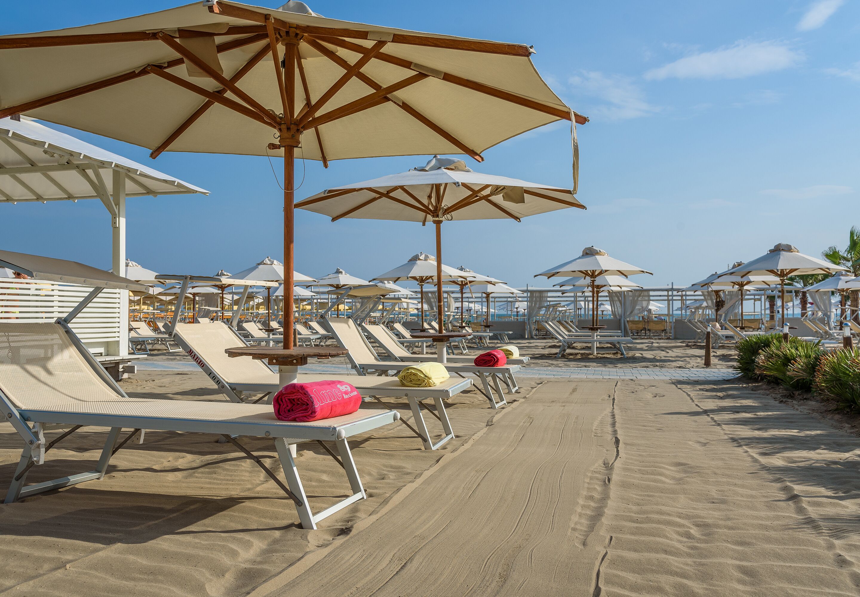 Un área de descanso en la playa con varias tumbonas y sombrillas grandes.