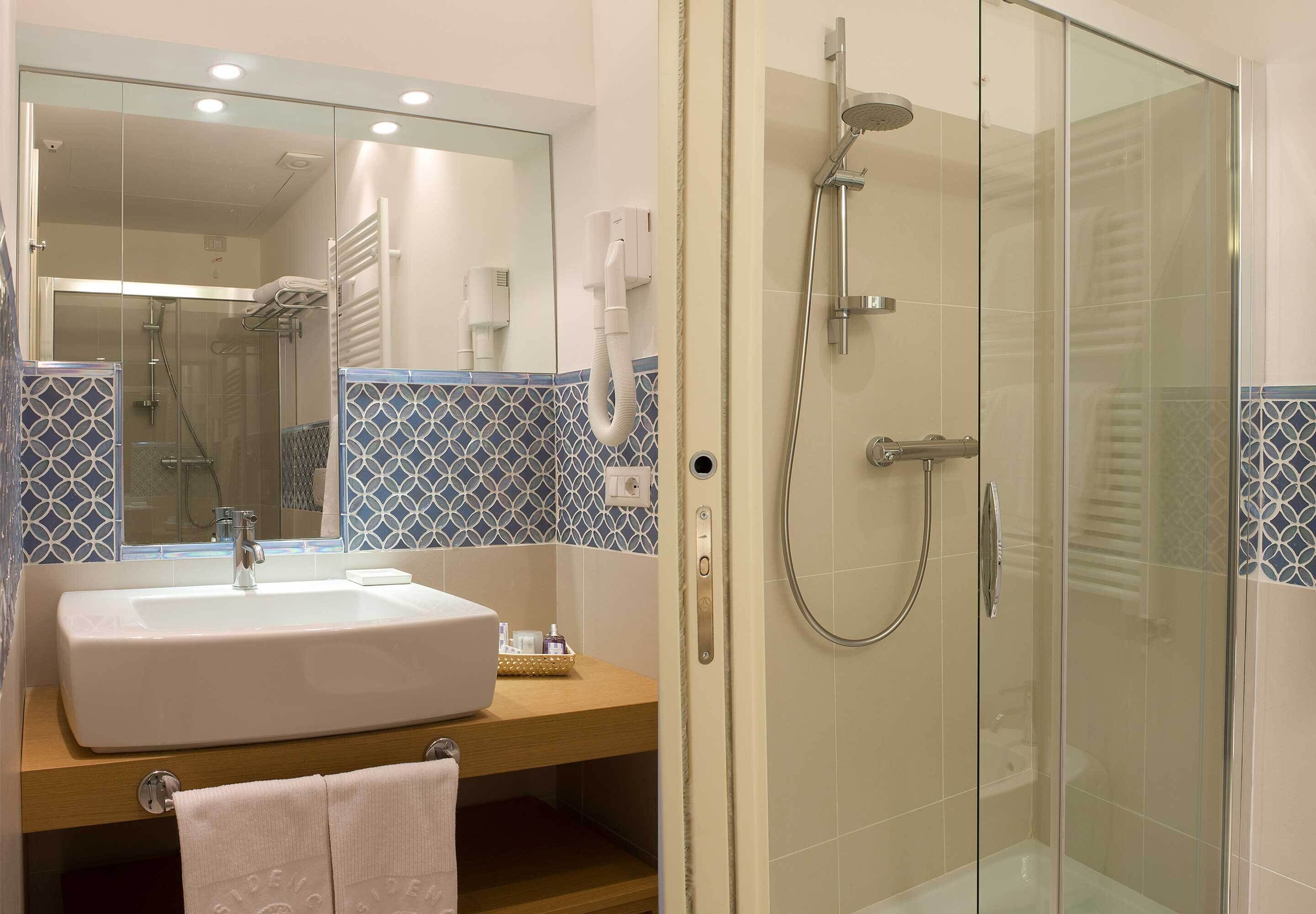 Un bagno moderno con cabina doccia in vetro, lavandino con asciugamano e specchio.