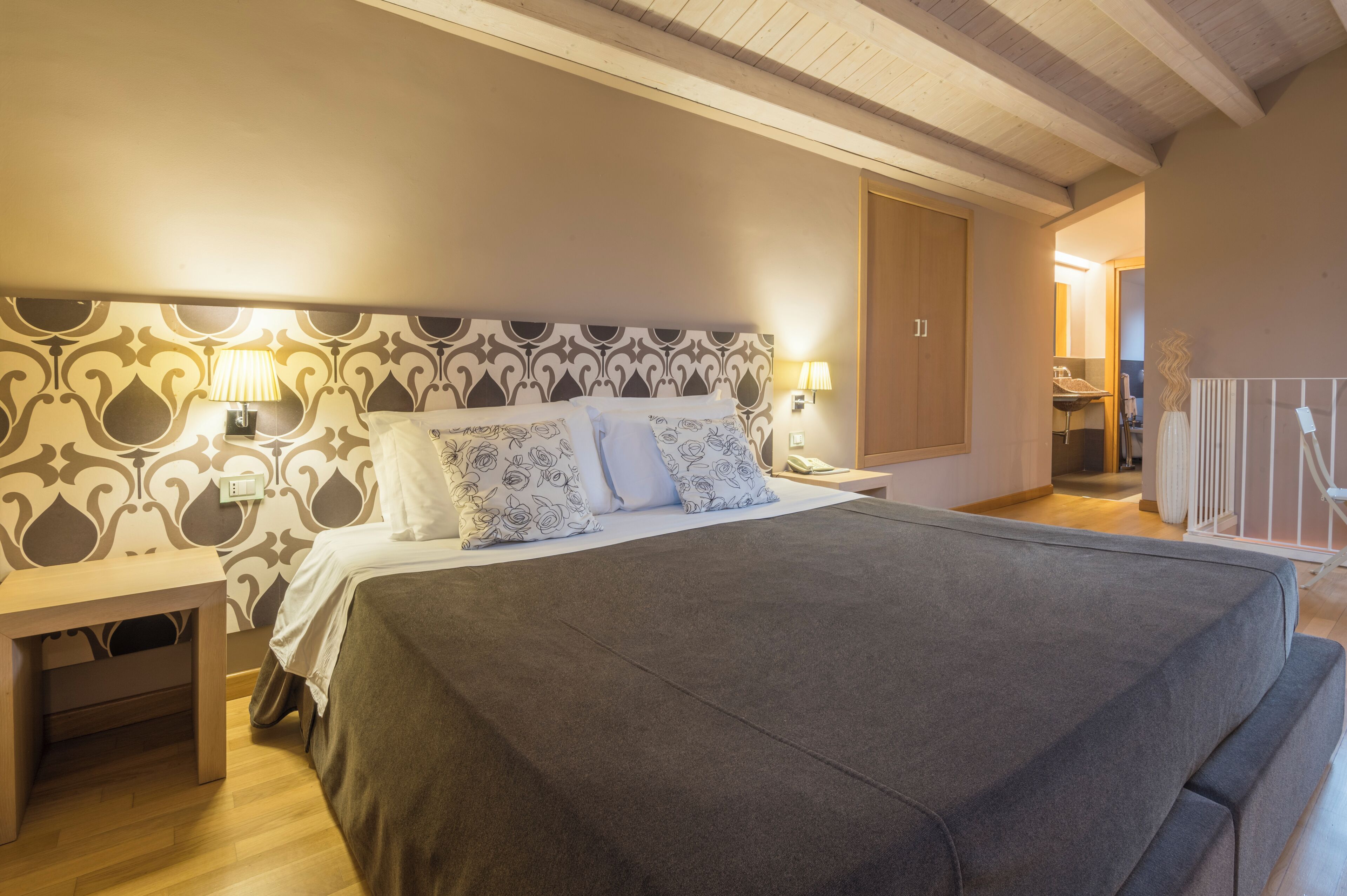 Una camera da letto ordinata con un letto grande, due comodini e una testiera decorata.