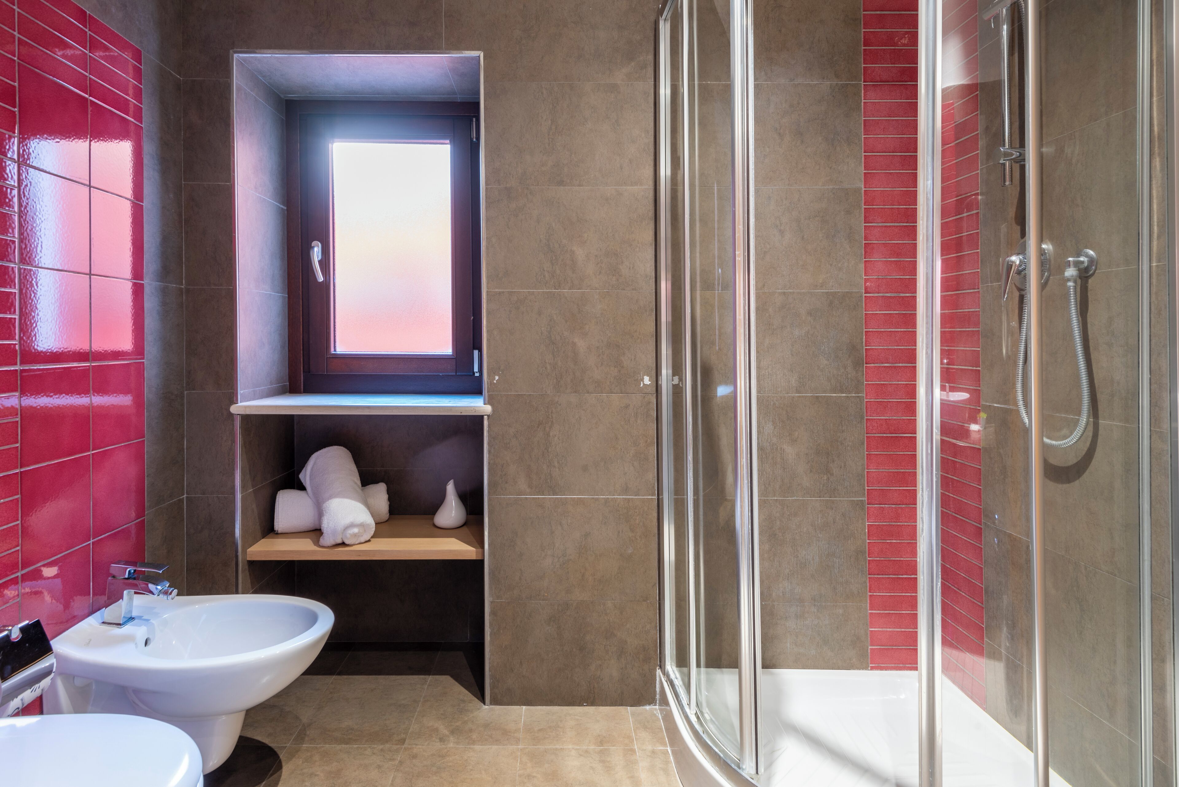A modern bathroom with a glass shower enclosure, a bidet, and a vanity with a mirror.