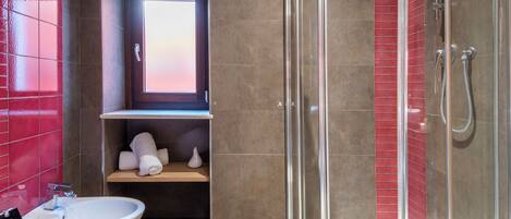 A modern bathroom with a glass shower enclosure, a bidet, and a vanity with a mirror.