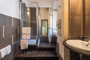 Un baño moderno con ducha de vidrio, un lavabo grande y un espejo.