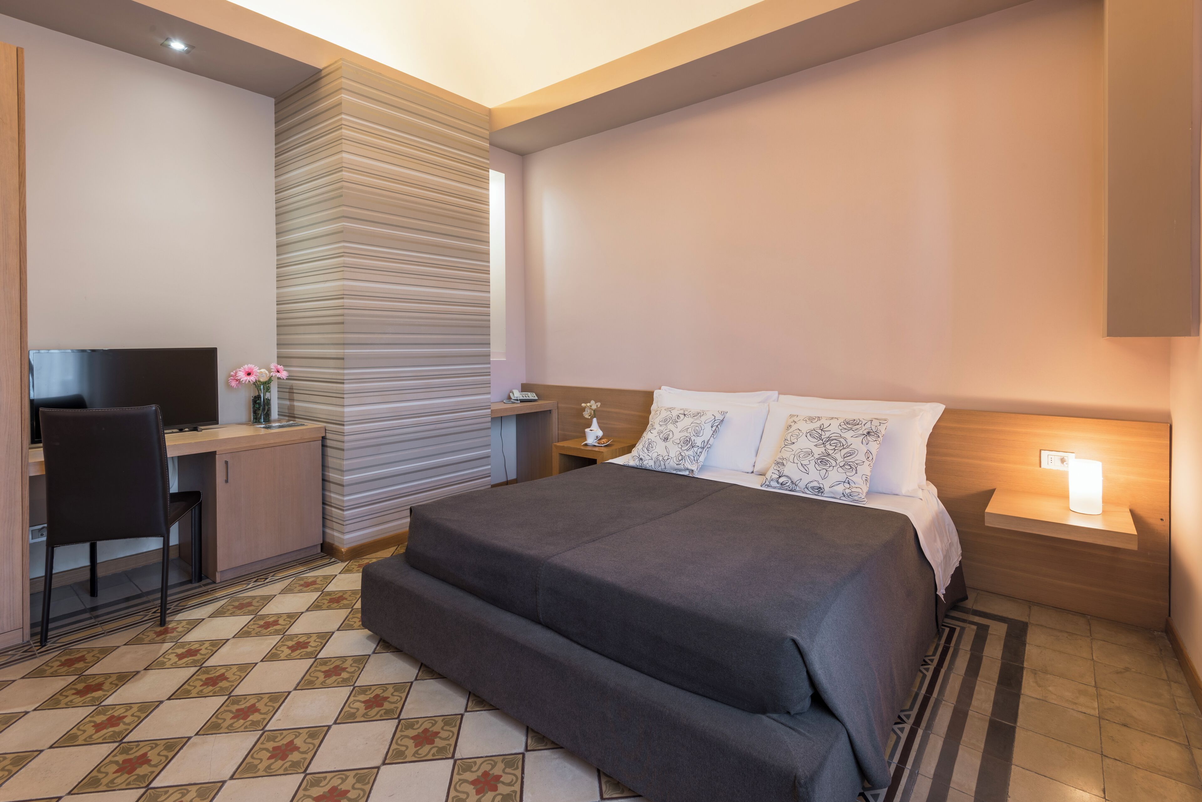 Una habitación de hotel moderna con una cama, un escritorio y un televisor.