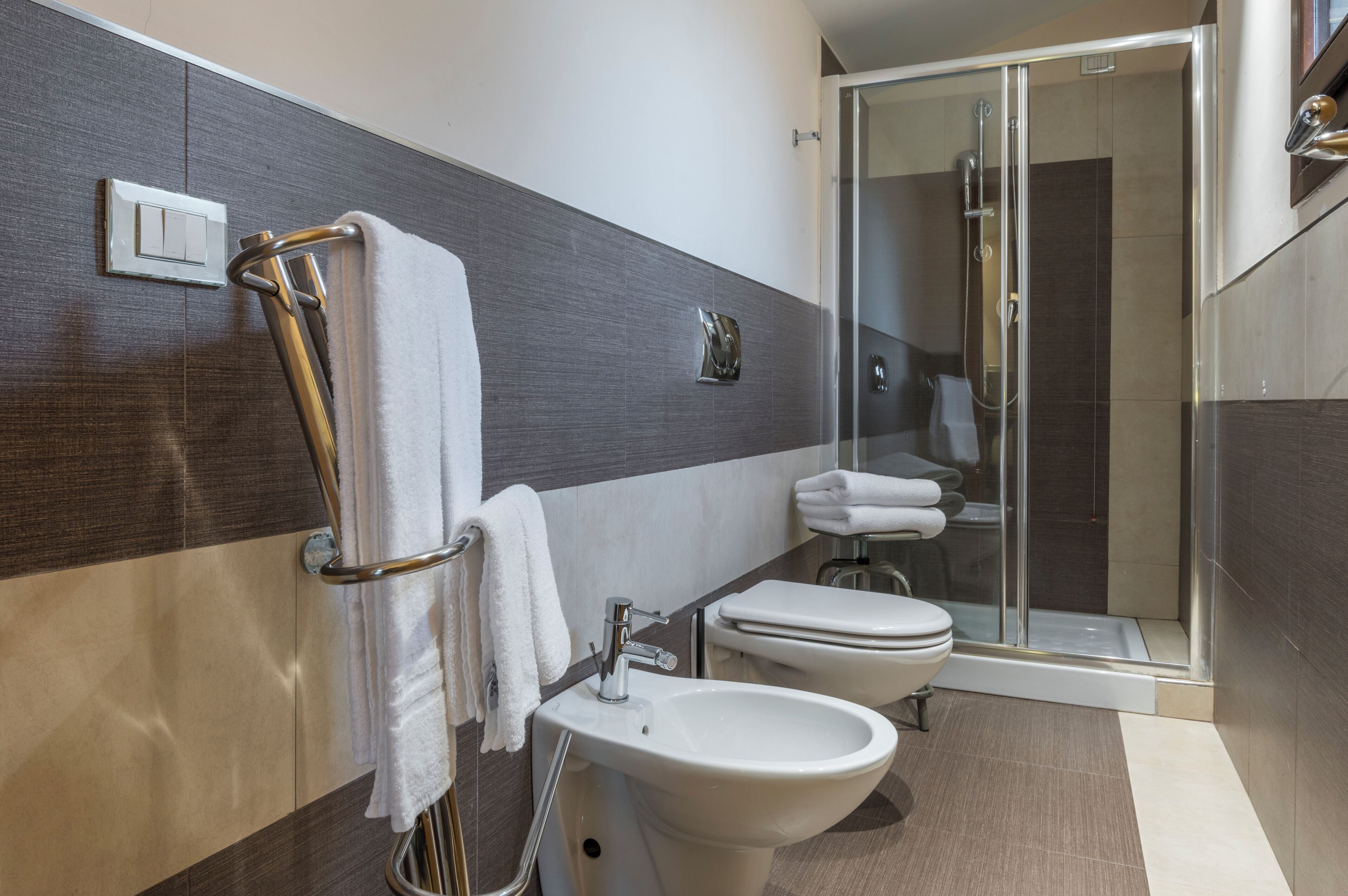 A modern bathroom with a glass shower enclosure, a bidet, and a toilet.