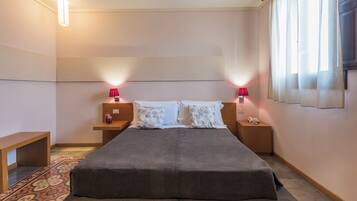 Una habitación de hotel moderna con una cama grande, mesitas de noche con lámparas, una mesita auxiliar de madera y una alfombra estampada.