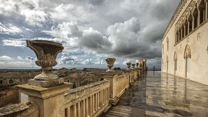 A long corridor with ornate columns and a view of the cityscape.