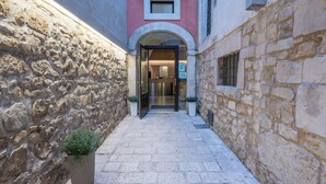 A narrow stone corridor with a door leading to a room.