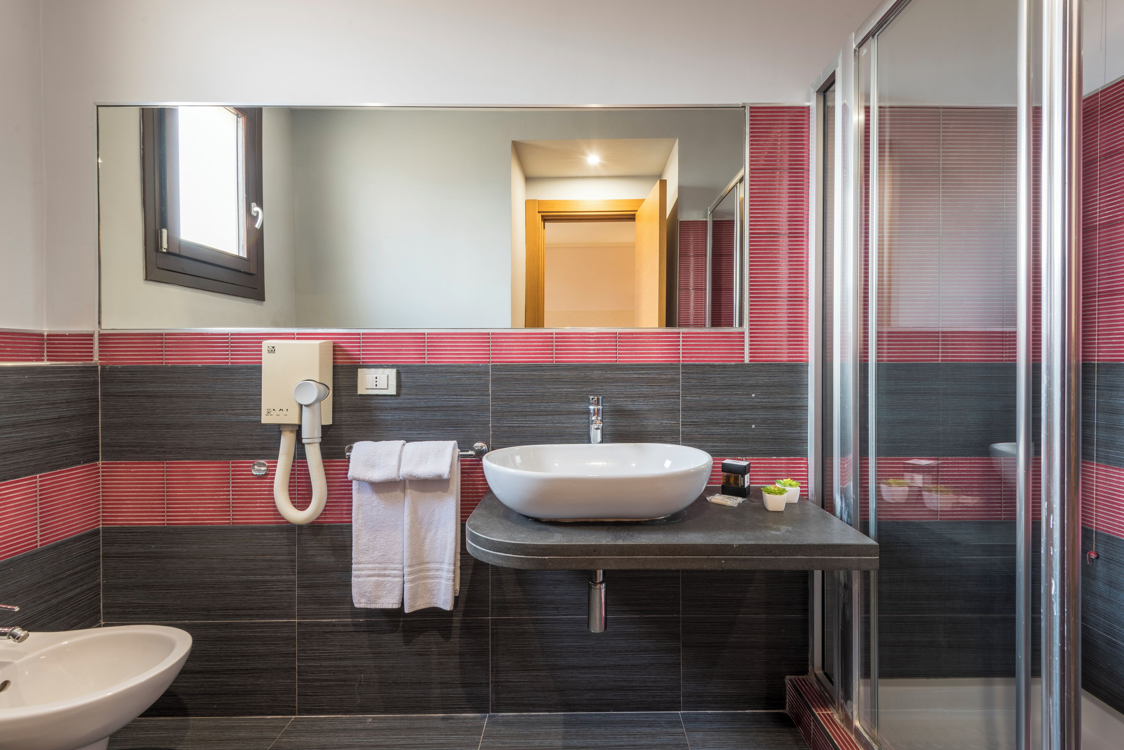 A modern bathroom with a large sink, a mirror, and a shower area.