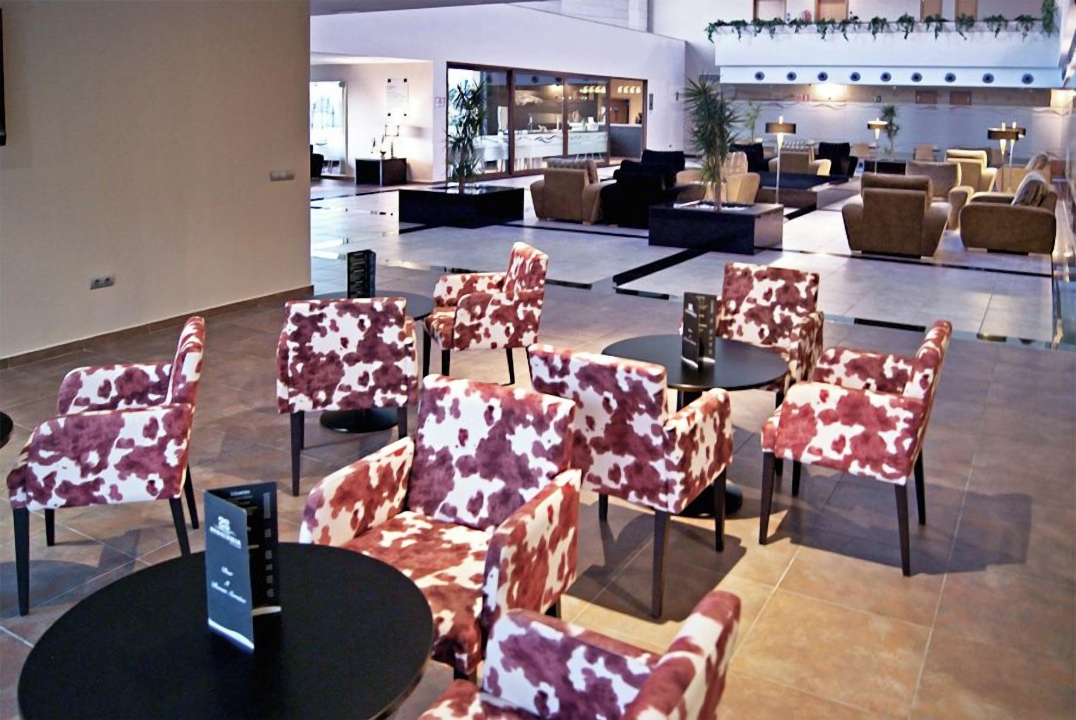 Un hall d’entrée doté de plusieurs espaces de détente, comprenant des chaises et des canapés, ainsi qu’un comptoir d’accueil.