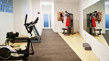 Un gimnasio con equipo cardiovascular, máquinas de pesas y un espejo en la pared.