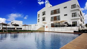 Een buitenzwembad, parasols voor strand/zwembad