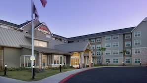 A Marriott Residence Inn with a modern design, featuring a stone facade, multiple windows, and a flagpole with an American flag. - Residence Inn by Marriott San Antonio SeaWorld/Lackland (San Antonio)