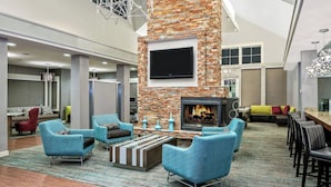 A spacious lounge area with a stone fireplace, comfortable seating, and a flat-screen TV mounted on the wall. - Residence Inn by Marriott San Antonio SeaWorld/Lackland (San Antonio)