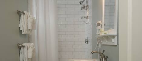 Un baño con lavamanos blanco, un espejo y cabina de ducha.