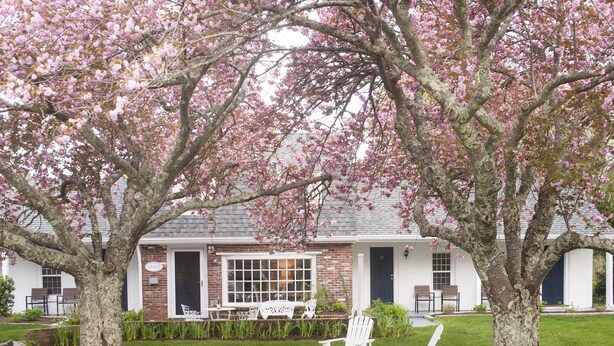 A house with a brick exterior, white exterior walls, and a front porch with white chairs.