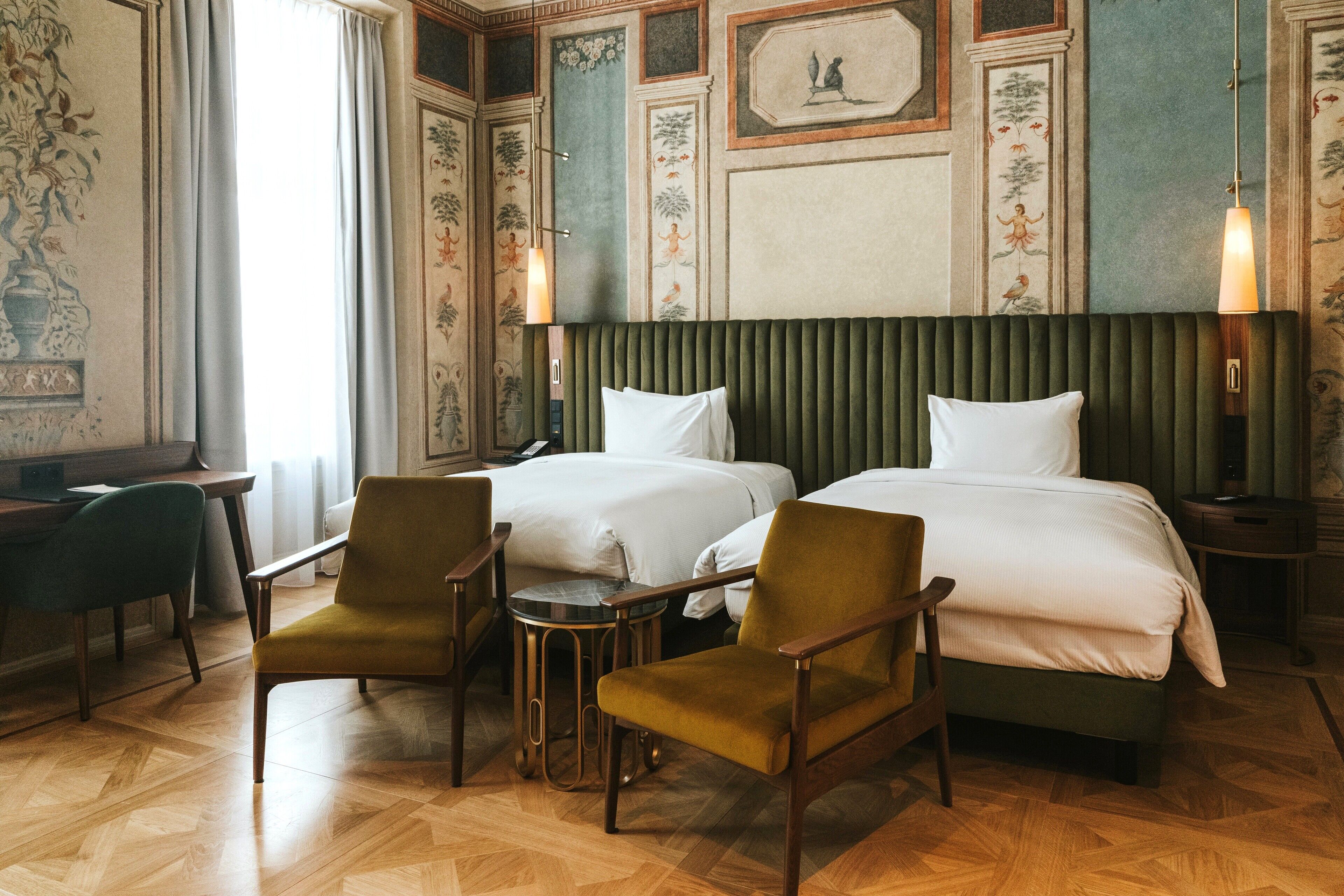 Une chambre d’hôtel avec deux lits, un bureau et deux chaises.