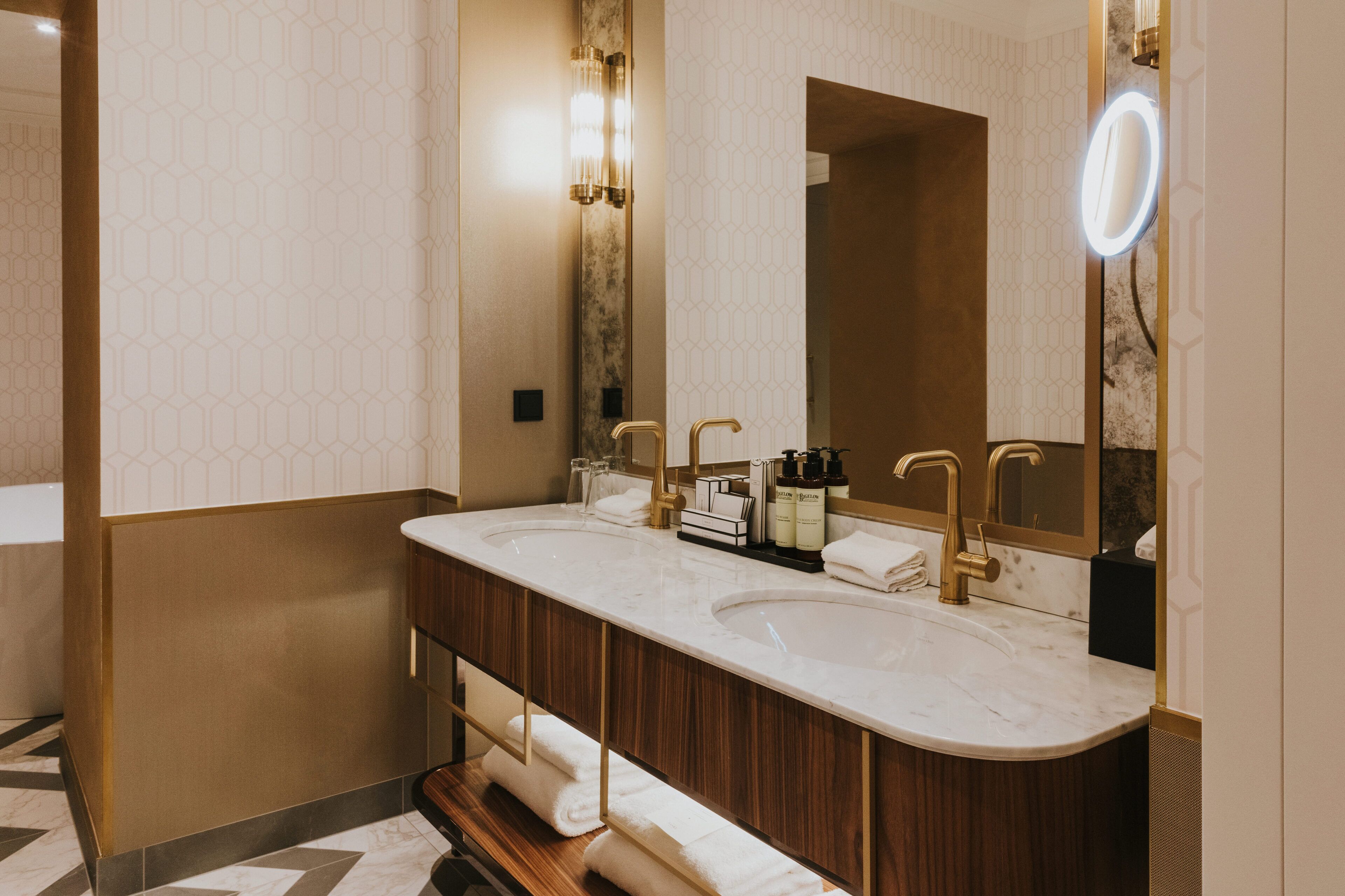 A modern bathroom with two sinks, a large mirror, and a vanity with a wooden cabinet.