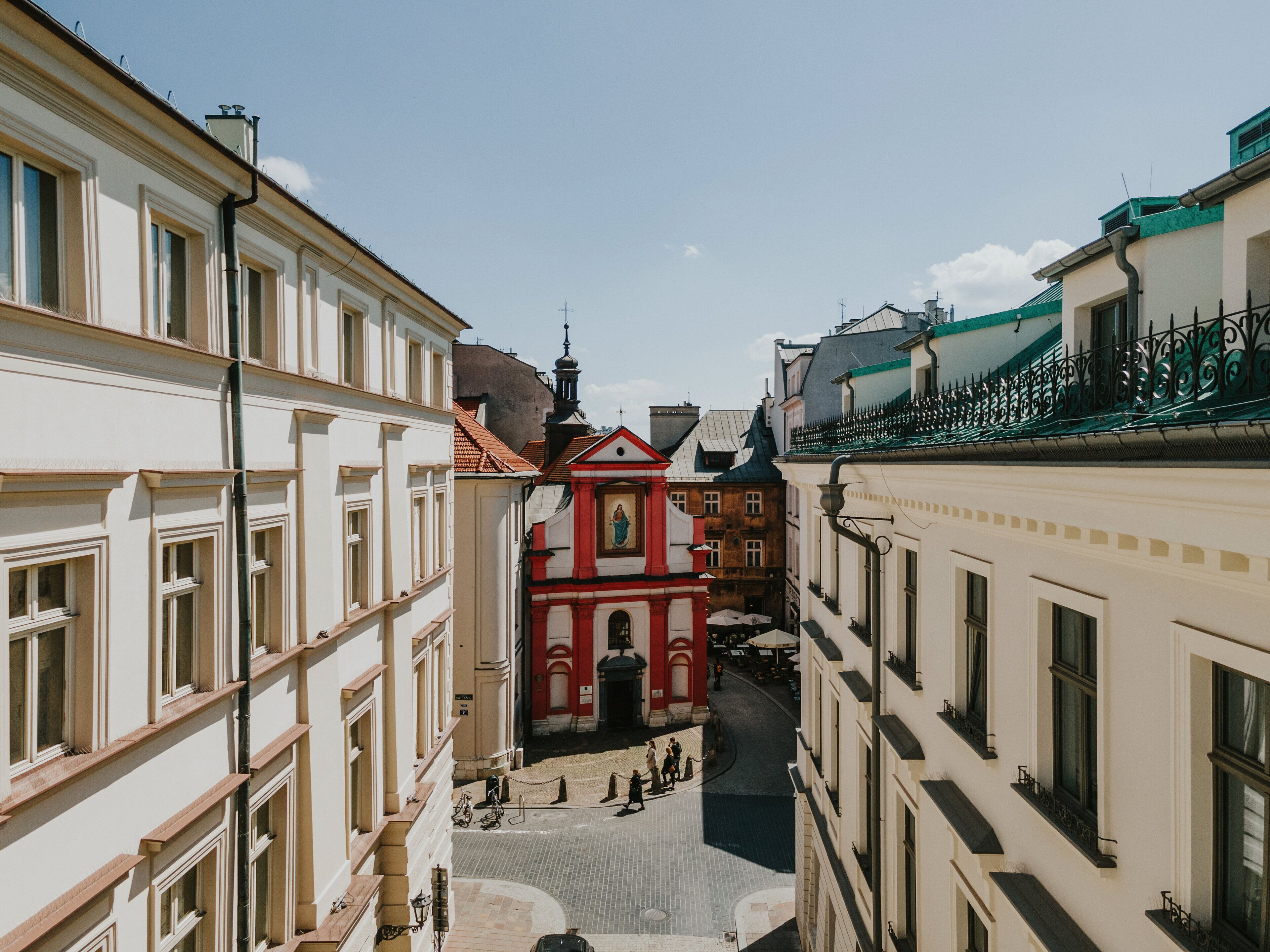 Une rue étroite bordée de bâtiments des deux côtés, une église rouge avec un clocher et une rue pavée.
